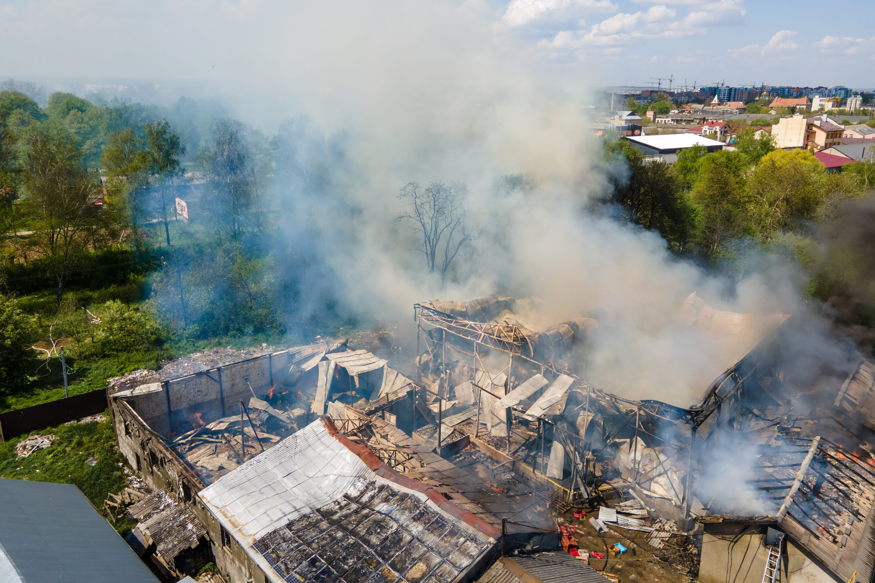 Aerial view of ruined building on fire with collapsed roof and rising dark smoke